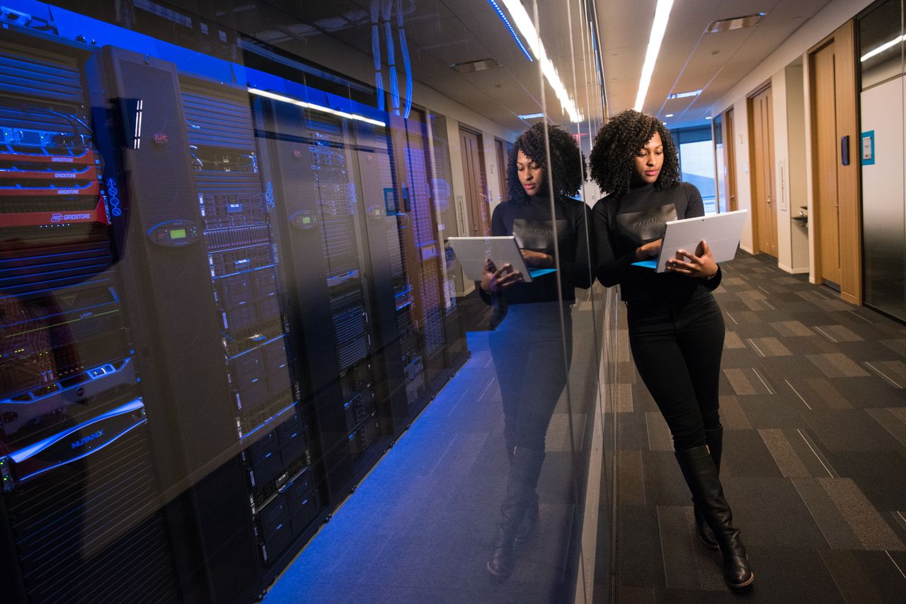 Mastering the First Impression: Your intriguing post title goes here A woman using a laptop navigating a contemporary data center with mirrored servers.