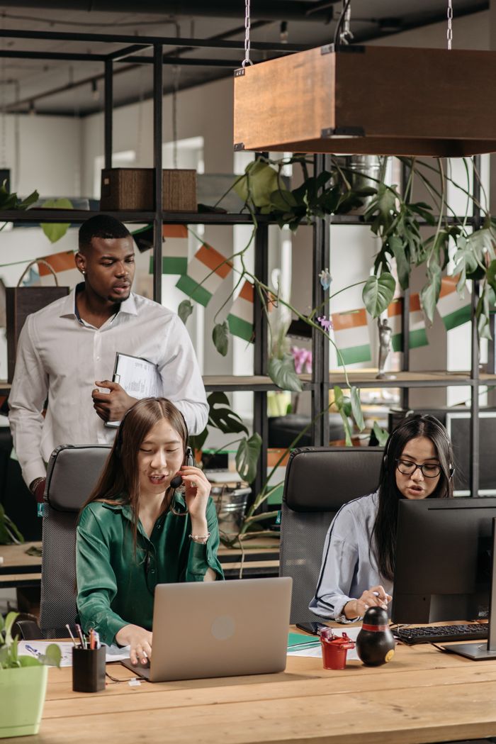 Crafting Captivating Headlines: Your awesome post title goes here Colleagues in an office setting collaborating on tasks with technology and decor around them.
